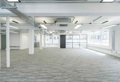 Bright open-plan workspace with grey carpet and industrial ceiling details.