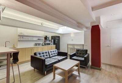 Modern communal kitchen and breakout lounge with black leather sofas and a red feature pillar.