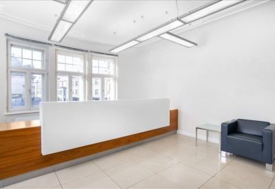 Minimalist reception area featuring a white and wood desk and leather armchair.