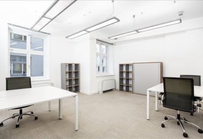 Bright open-plan office with white desks and shelving units.
