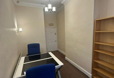 Private office featuring blue chairs, a modern desk, and a decorative ceiling rose.