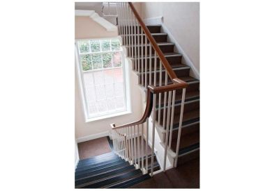 Staircase with wooden handrails and white spindles next to a large window.