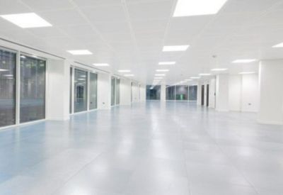 Bright, white open-plan workspace with large floor-to-ceiling windows and reflective flooring.