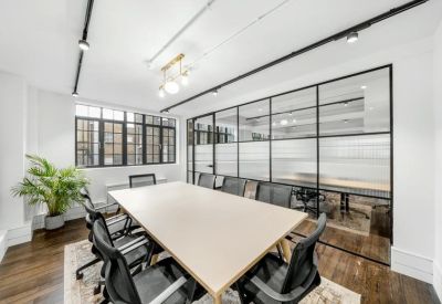 Bright boardroom with a large table, black mesh chairs, and glass partition walls.
