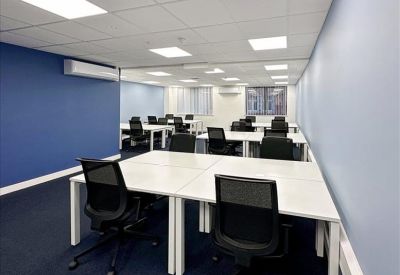 Open-plan office with white desks, black mesh chairs, and a blue feature wall.
