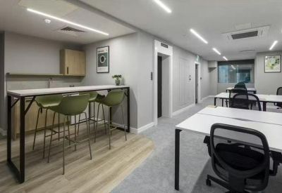 Bright communal break area with a high-top breakfast bar and green stools.