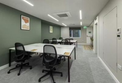 Open-plan office space featuring white desks and olive green accent walls.