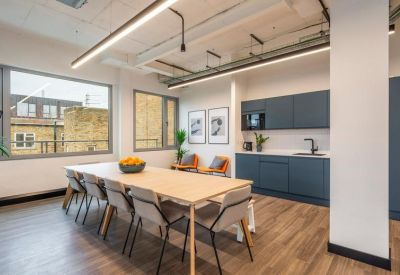 Modern kitchen and dining area featuring blue cabinetry and a long light wood communal table.