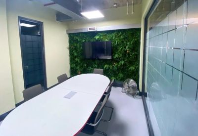 Modern meeting room with an oval white table and a vibrant green moss feature wall.