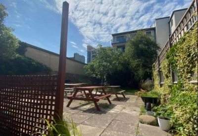 Outdoor terrace with wooden picnic benches and stone paving.