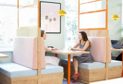 Private wooden meeting booths with pink cushions and orange glass partitions.