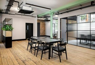Modern coworking area with a black meeting table and glass-partitioned office walls.
