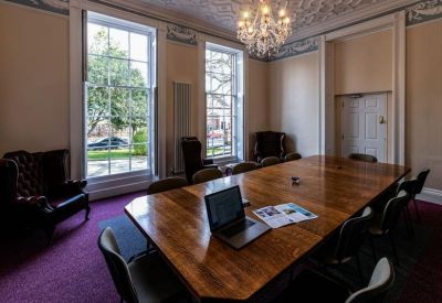Grand meeting room featuring a large wooden table, chandelier, and ornate ceiling.