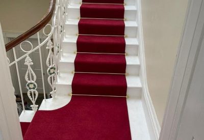 Staircase with white decorative railings and a red carpet runner.