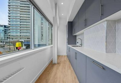 Narrow galley kitchen with grey cabinetry and large windows overlooking the city.