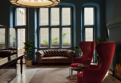 Elegant lounge area featuring a tufted leather sofa and plush red wingback chairs.