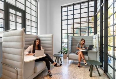 Modern lobby area with a sleek white front desk and a bicycle parked by the window.