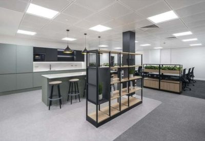 Modern communal kitchen and breakout area with a large island and shelving divider.