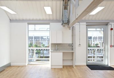 Bright communal kitchenette with white cabinetry and large windows.