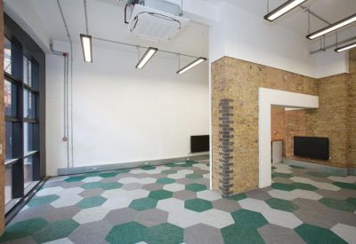 Minimalist workspace featuring green and grey hexagonal carpet tiles and exposed brick pillars.