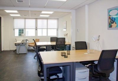 Modern boardroom with a light wood table, black mesh chairs, and copper pendant lights.