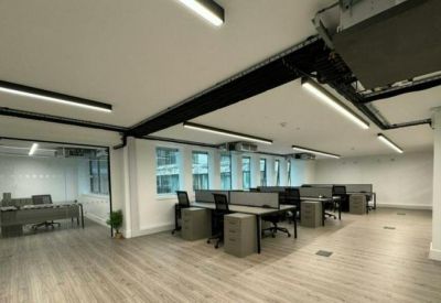 Spacious open-plan office with grey workstations, ergonomic chairs, and linear LED lighting.