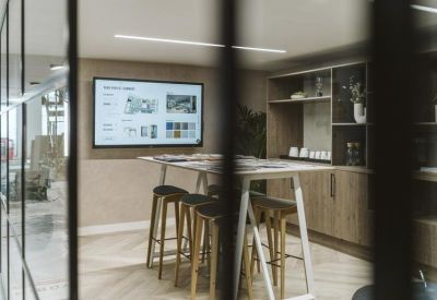 Modern meeting space featuring a wall-mounted screen and high bar stools.