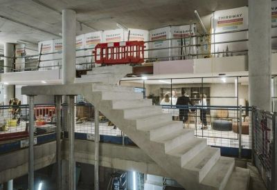 A concrete staircase under construction viewed from a finished office level.