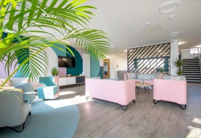 Spacious reception lounge with pink sofas and a geometric mural.