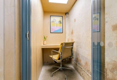 Quiet one-person focus booth with a built-in desk, tan chair, and framed wall art.