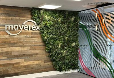 Branded reception area featuring a wall of moss and a wooden panel with the Maverex logo.