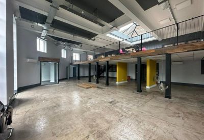 Spacious industrial-style open plan office with high ceilings and mezzanine level.