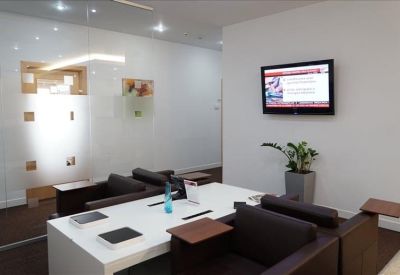 Modern lounge area with comfortable black armchairs and a wall-mounted TV screen.