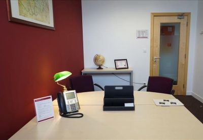 Private office featuring a red accent wall, traditional green desk lamp, and a desk globe.