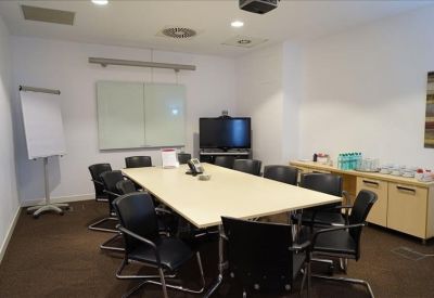 Professional meeting room with a large table, black leather chairs, and a whiteboard.