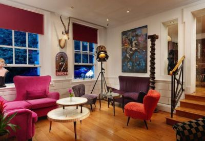 Stylish lounge area with vibrant pink and purple armchairs and wooden floors.