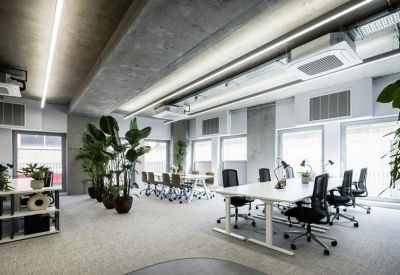 Bright workspace featuring rows of white desks and integrated ceiling lighting.