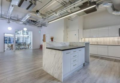 Kitchenette and breakout area with marble-effect island and sleek white cabinetry.