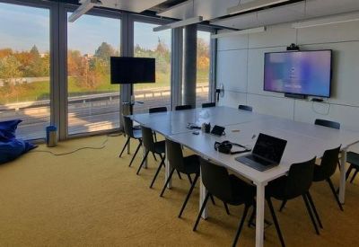Professional conference room with a large white table and wall-mounted screen.