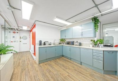 Modern communal kitchen with blue cabinetry and wood flooring.
