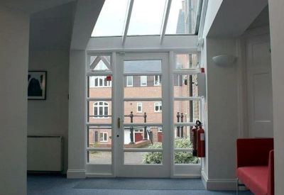 Bright workspace area with a large glass door overlooking a courtyard and a red sofa for seating.