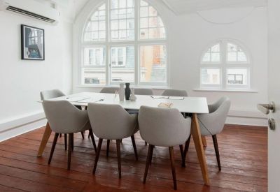 Spacious meeting room with grey chairs and views through an arched window.