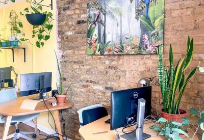 Modern workspace with wooden desks, computer monitors, and an exposed brick wall.