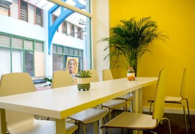 Bright meeting area with a long white table set against a vibrant yellow wall.