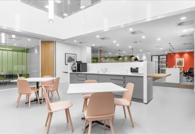 Communal kitchen and dining area with modern grey cabinetry and wooden chairs.