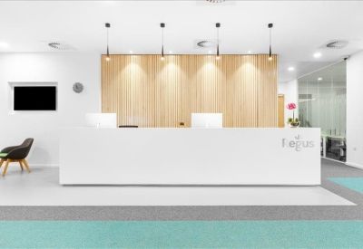 Bright reception area featuring a white minimalist desk and light wood panelled wall.