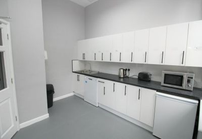 Modern communal kitchen with white cabinetry and dark countertops.