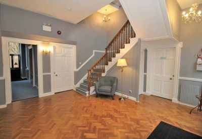 Spacious reception area featuring parquet wood flooring and a grand staircase.