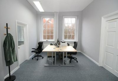Bright two-person office suite with grey carpets and large windows.
