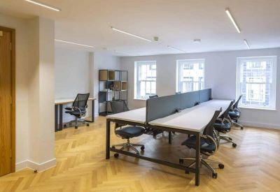 Modern office space with large windows and a central desk pod separated by privacy screens.